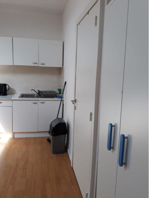Cuisine moderne avec armoires blanches et parquet en bois à la Résidence Mantekila, Marcinelle