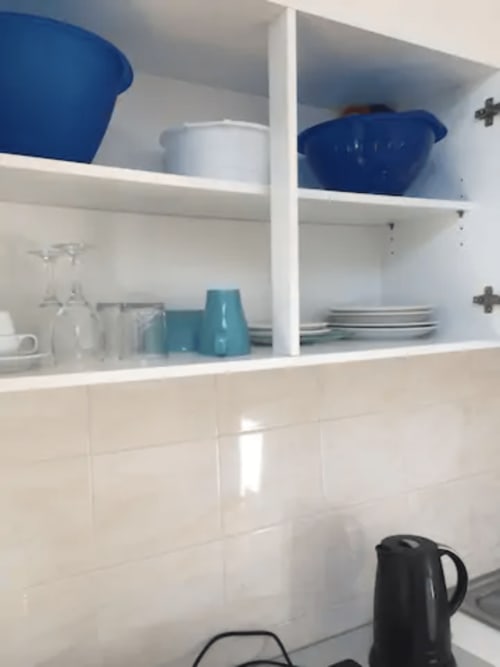 Étagères ouvertes blanches dans l'appartement Résidence Mantekila avec bols bleus, tasses turquoise et assiettes blanches
