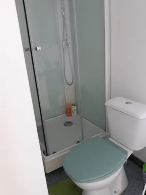 Petite salle de bain de l'appartement Résidence Mantekila avec douche, toilettes et sanitaires blancs à Marcinelle