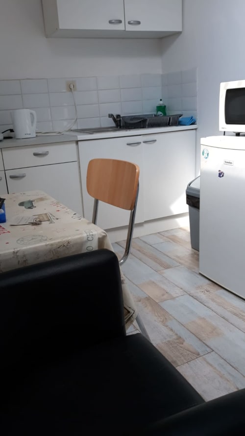 Cuisine de l'appartement Résidence Mantekila à Marcinelle avec meubles blancs, table à manger et électroménagers