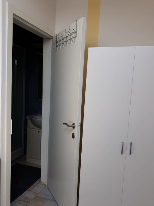 Couloir moderne de l'appartement Résidence Mantekila à Marcinelle, avec armoire blanche et entrée salle de bains