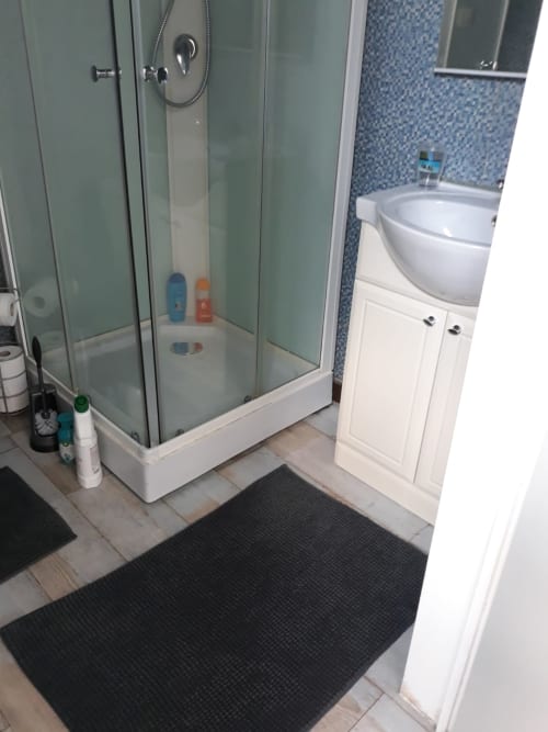 Salle de bain moderne à la Résidence Mantekila avec douche à l'italienne, meuble vasque blanc et carrelage mosaïque bleu