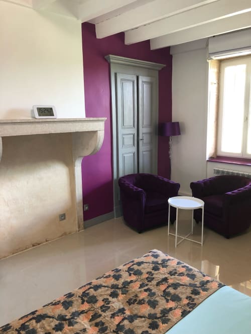 Coin salon cosy à La Ferme du Bonheur B&B à Arbigny avec murs accentués de violet, fauteuils en velours et cheminée