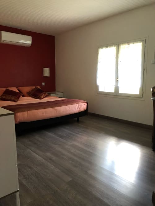 Chambre moderne à La Ferme du Bonheur avec mur d'accent rouge, lit queen-size et portes vitrées donnant sur la lumière naturelle