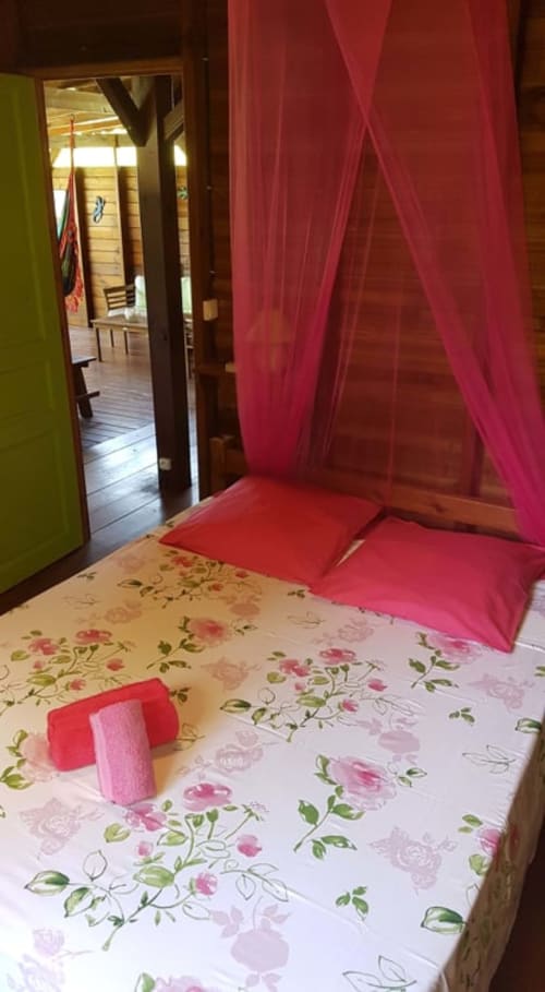 Lit à baldaquin rose dans villa aux Hauts de Deshaies, Deshaies avec literie fleurie et vue sur mer