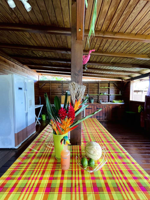 Intérieur coloré de la villa Les Hauts De Deshaies avec fleurs tropicales, poutres en bois et chemin écossais aux teintes vives à Deshaies,