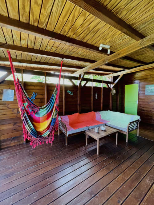 Hamac coloré et lits dans villa en bois aux Hauts de Deshaies avec vue sur la mer