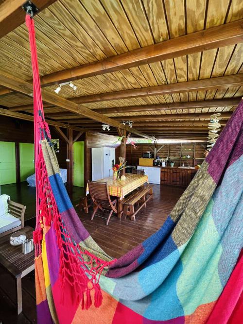 Hamacs colorés sur terrasse en bois avec vue sur la salle à manger de la villa Les Hauts De Deshaies à Deshaies