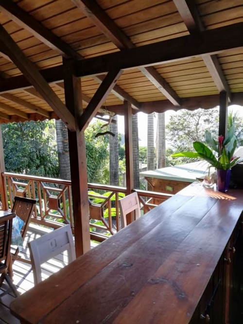 Pergola en bois avec espace repas aux Hauts De Deshaies, vue océan, plantes tropicales et terrasse d'appartement