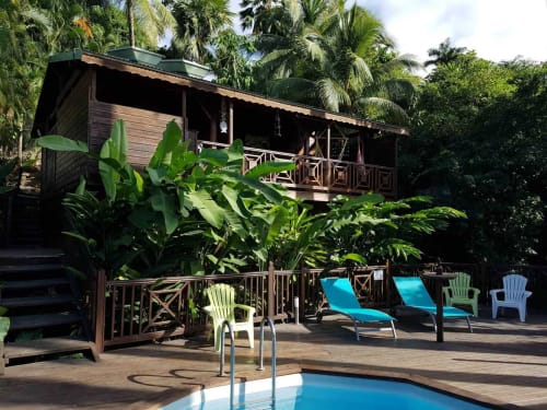 Piscine tropicale aux Hauts de Deshaies avec transats, palmiers et bungalow en bois à Deshaies