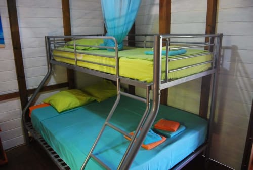 Lits superposés avec literie jaune et bleu dans un appartement à Deshaies à l'hôtel Les Hauts De Deshaies