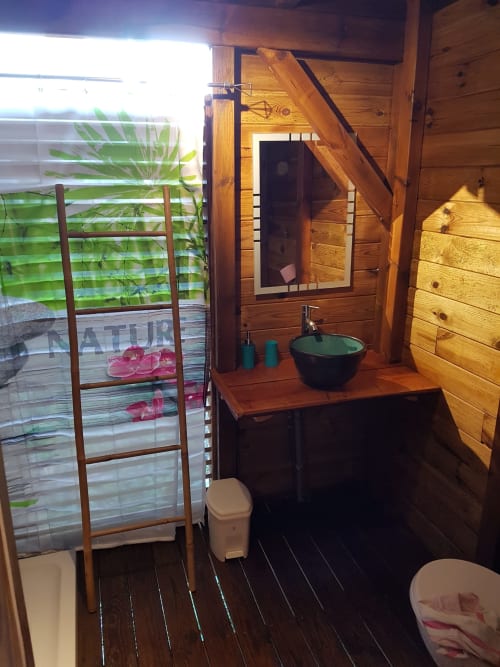 Salle de bain rustique en bois avec vue sur mer aux Hauts de Deshaies, vasque noire et lumière naturelle