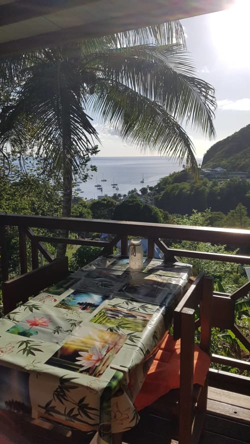Balcon surplombant la mer des Caraïbes aux Hauts de Deshaies, Guadeloupe avec palmiers et voiliers