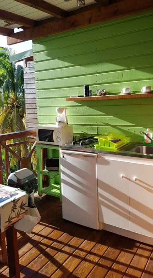 Kitchenette vert vif avec appareils blancs et étagères en bois aux Hauts De Deshaies, Deshaies