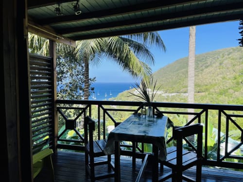 Terrasse vue mer aux Hauts de Deshaies avec table de salle à manger surplombant la baie et les collines verdoyantes