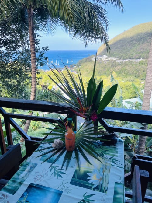 Composition florale tropicale sur la terrasse avec vue sur les voiliers aux Hauts de Deshaies, Guadeloupe