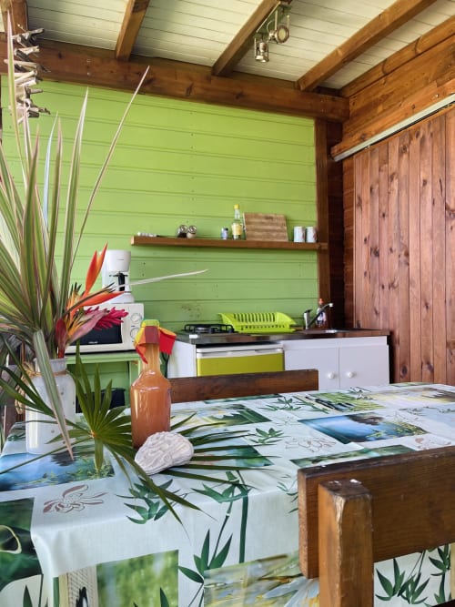 Cuisine tropicale lumineuse aux Hauts de Deshaies avec murs vert citron, poutres en bois et décor botanique