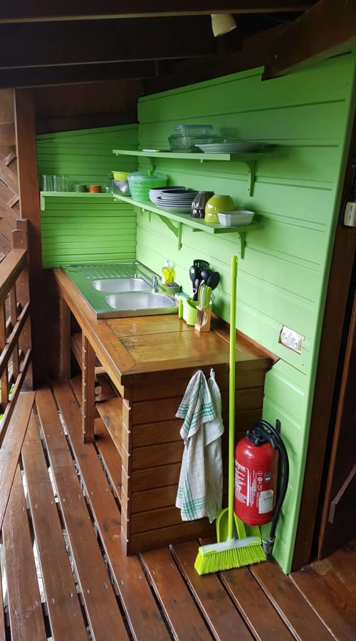 Kitchenette compacte aux murs vert vif, double évier, étagères, ustensiles de cuisine et extincteur aux Hauts De