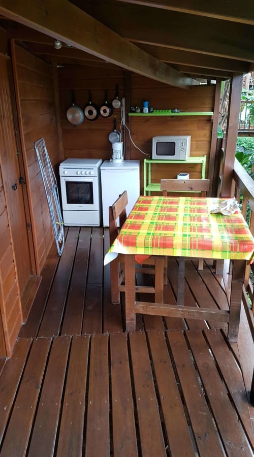 Petite kitchenette équipée d'une cuisinière, d'un four à micro-ondes et d'une table à manger dans l'appartement Les Hauts De Deshaies à Deshaies