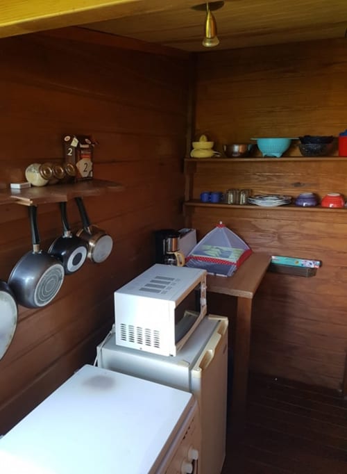 Intérieur de cuisine de cottage aux Hauts de Deshaies avec étagères en bois, ustensiles de cuisine et appareils électroménagers à Deshaies
