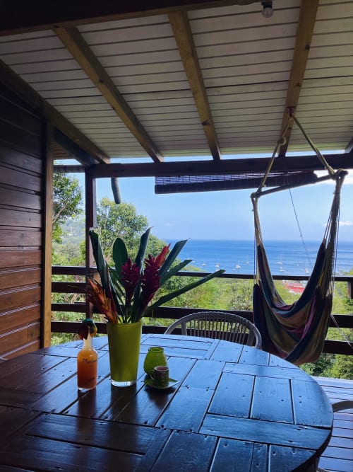 Terrasse de gîte vue mer aux Hauts de Deshaies avec hamac, fleurs et vista caribéen