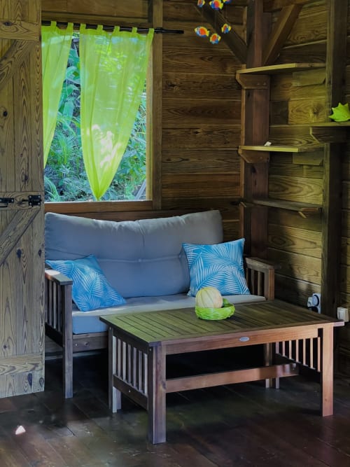 Intérieur douillet du cottage Les Hauts De Deshaies avec sièges bleus, mobilier en bois, rideaux vert tropical