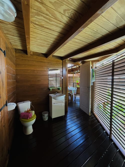 Salle de bain en bois avec toilettes, lavabo et murs à jalousies aux Hauts de Deshaies, Deshaies