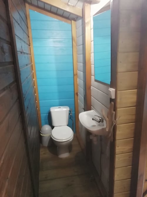 Salle de bain du cottage aux Hauts de Deshaies avec carrelage turquoise, toilettes, lavabo et finitions en bois