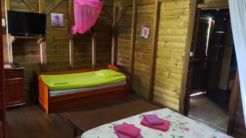 Chambre de cottage aux Hauts de Deshaies avec murs en bois, lits colorés, décor rose et vue sur la mer à Deshaies