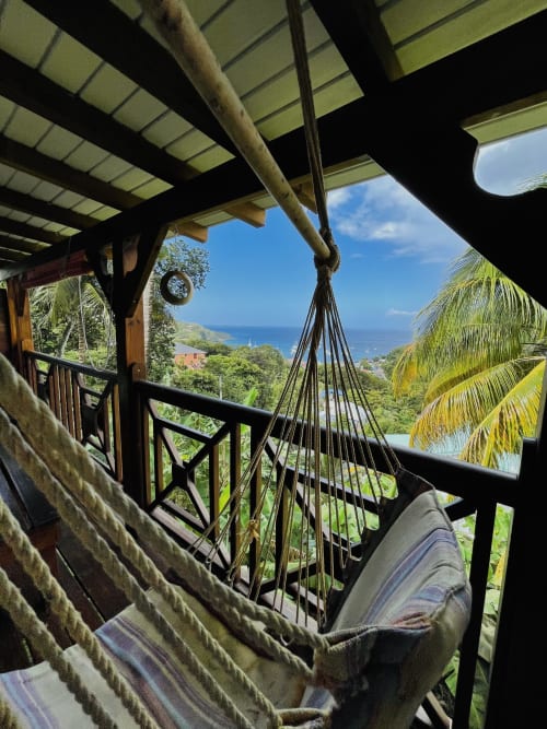Vue du hamac depuis le balcon des Hauts De Deshaies surplombant le jardin tropical et la mer des Caraïbes