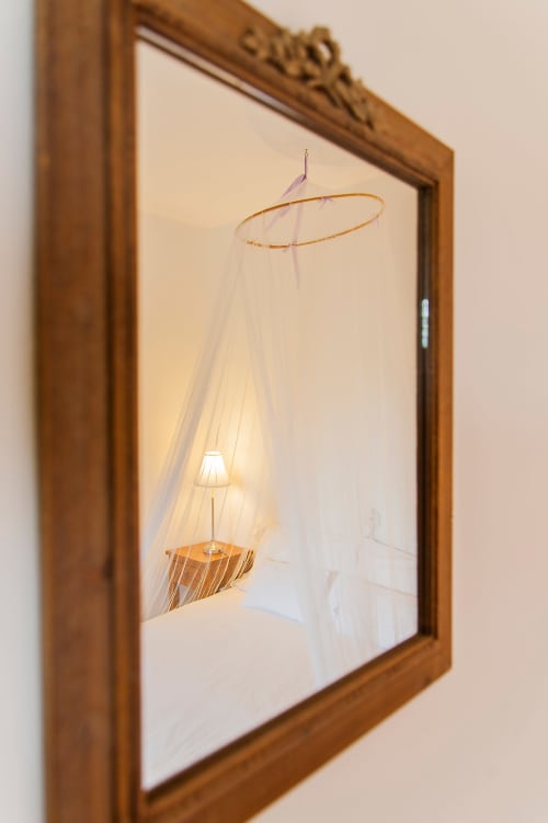 Mosquito net canopy with wooden frame and hanging lamp in Casa Rural La Perla bedroom with garden view