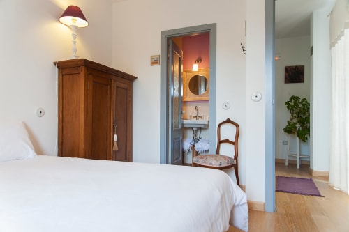 Chambre spacieuse à Casa Rural La Perla avec literie blanche, armoire en bois et salle de bain attenante visible par la porte