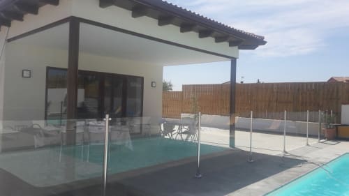 Terrasse de cottage moderne avec pergola ombragée, clôture de piscine en verre et piscine turquoise à Casa Rural La Perla