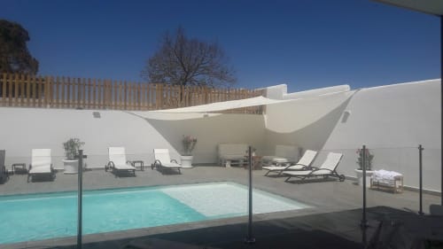 Piscine de la Casa Rural La Perla avec transats, structures blanches d'ombrage et vue sur le jardin sous ciel dégagé