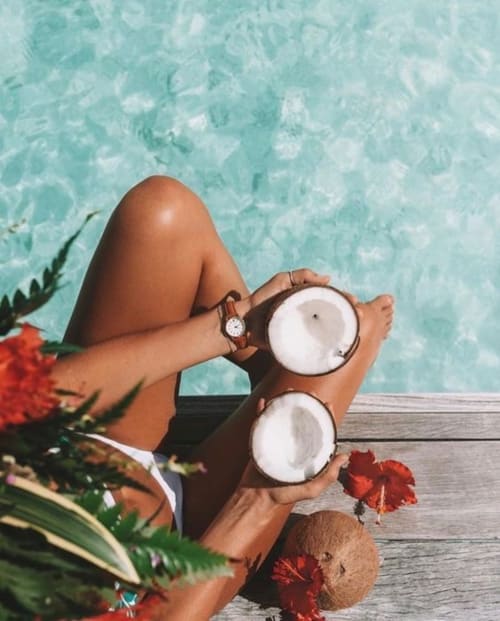 Person holding fresh coconuts by turquoise water at Habitation l'SEO resort in Sainte-Anne, Guadeloupe