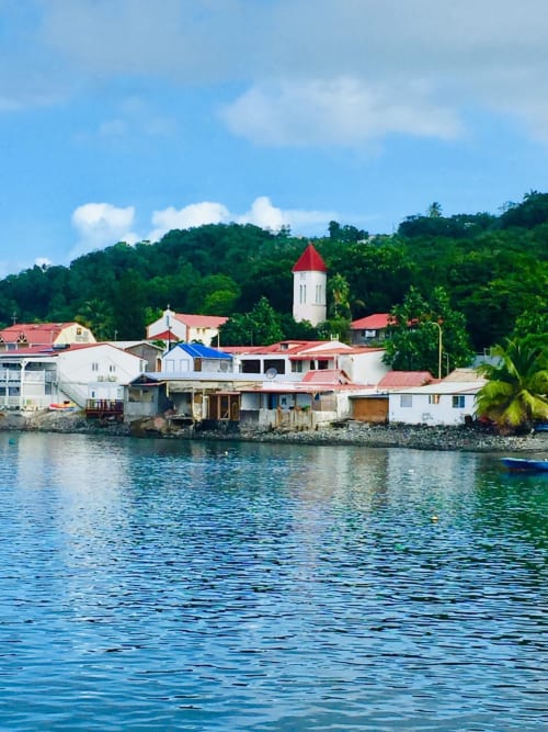 Vue du village côtier de Deshaies, Guadeloupe avec église, bâtiments colorés et eaux turquoise