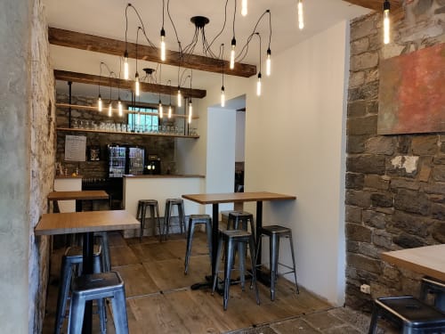 Bar contemporain de l'hôtel Le Moulin Des Ramiers à Crupet avec tables en bois, tabourets métalliques et luminaires industriels