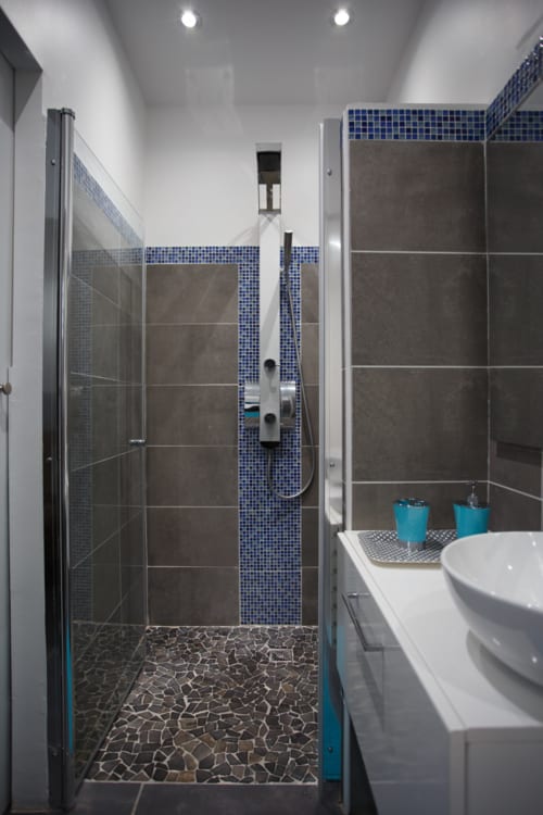 Salle de bains moderne du cottage Kaz A Bibi avec carrelage mosaïque bleu, douche ouverte, double vasque et luminosité généreuse