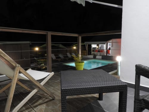 Vue nocturne du cottage Kaz A Bibi avec piscine illuminée, chaises longues et terrasse à Sainte-Rose, Guadeloupe