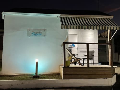 Entrée du gîte Kaz A Bibi illuminée la nuit à Sainte-Rose, Guadeloupe, avec façade éclairée et auvent rayé