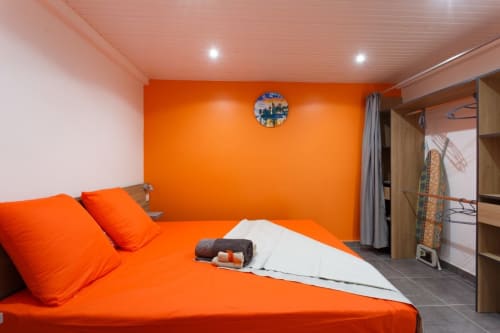 Chambre orange éclatante avec mobilier contemporain à la villa Kaz A Bibi à Sainte-Rose, Guadeloupe, linge de lit orange et