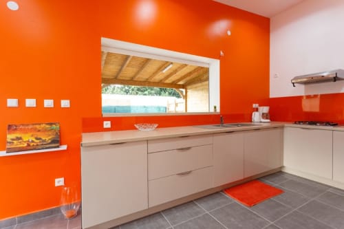 Cuisine moderne de la villa Kaz A Bibi à Sainte-Rose avec murs orange vif, mobilier beige et vue sur le jardin