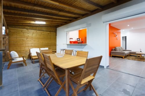 Salle à manger de la villa moderne à Kaz A Bibi avec table en bois, chaises et espace de vie ouvert aux touches orangées