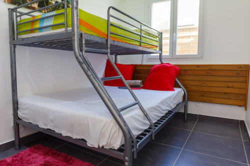 Lit superposé en métal avec draps blancs et oreillers rouges dans la chambre d'hôtes de Kaz A Bibi, Sainte-Rose