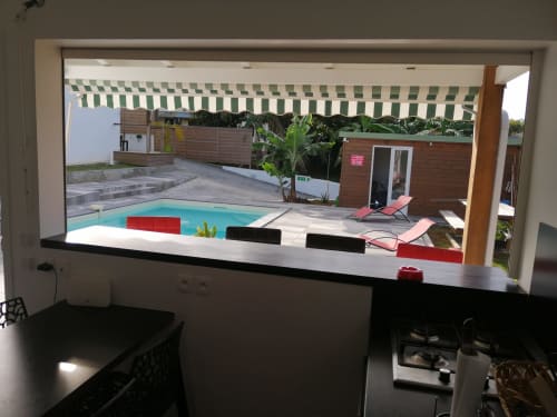 Vue de la piscine du cottage Kaz A Bibi depuis la fenêtre de la cuisine, Sainte-Rose, avec piscine turquoise et transats