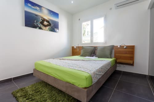 Chambre moderne à Kaz A Bibi à Sainte-Rose avec literie vert citron, tête de lit en bois et vue sur la piscine