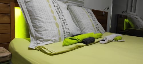 Chambre lumineuse vert citron à la Kaz A Bibi à Sainte-Rose avec serviettes bien disposées et coussins à motifs