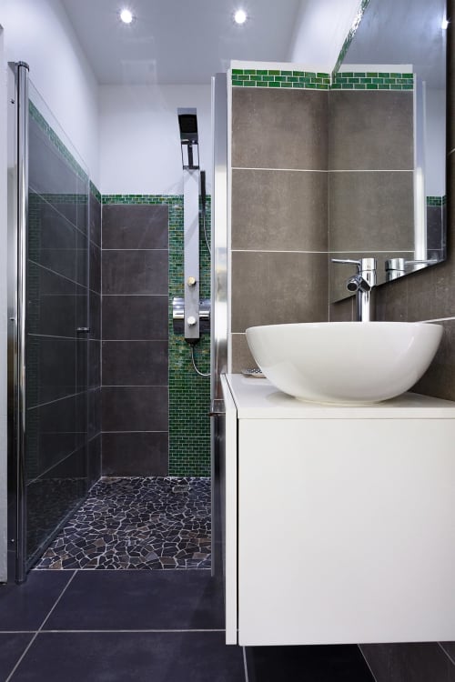 Salle de bain moderne du gîte Kaz A Bibi à Sainte-Rose avec vasque blanche, carrelage vert et douche à l'italienne
