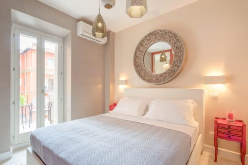 Camera moderna presso Petra Apartments Roma con letto queen, specchio circolare, porte balcone e comodino rosso