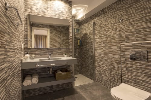 Baño moderno en Room Boutique 32 Denia con azulejos a rayas, lavabo de vanidad y ducha abierta